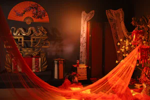 Композиция в китайском стиле с золотым драконом, красным веером на стене, троном, свитками с иероглифами и красной прозрачной тканью.